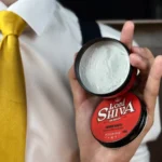 Pasta estilizadora Lord Shiva aberta mostrando textura cremosa com modelo de camisa social e gravata amarela.