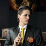 Close de modelo masculino com cabelo penteado para trás usando pomada de alto brilho.